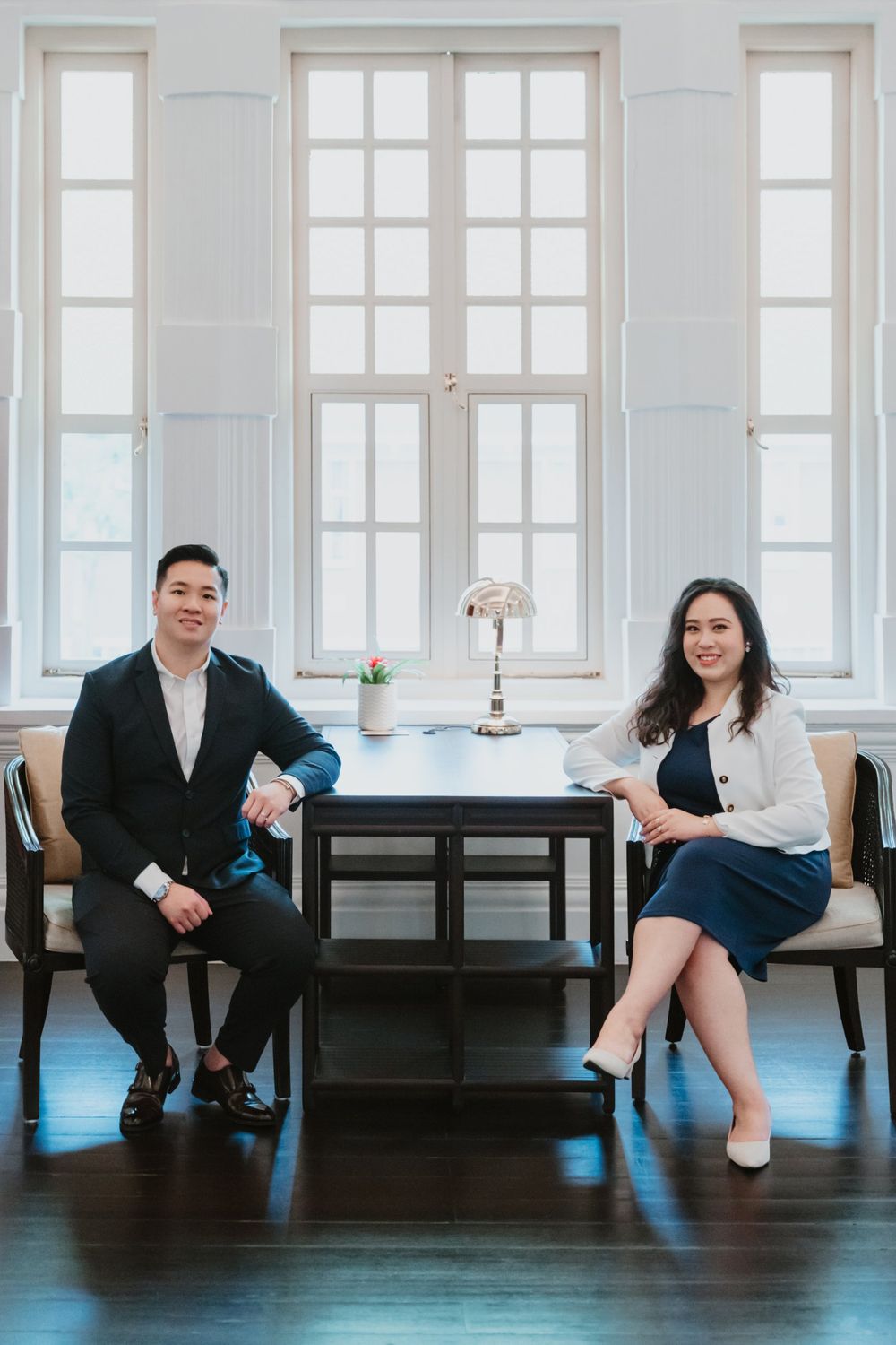 Keith and Rachel seated at a desk in front of tall colonial windows