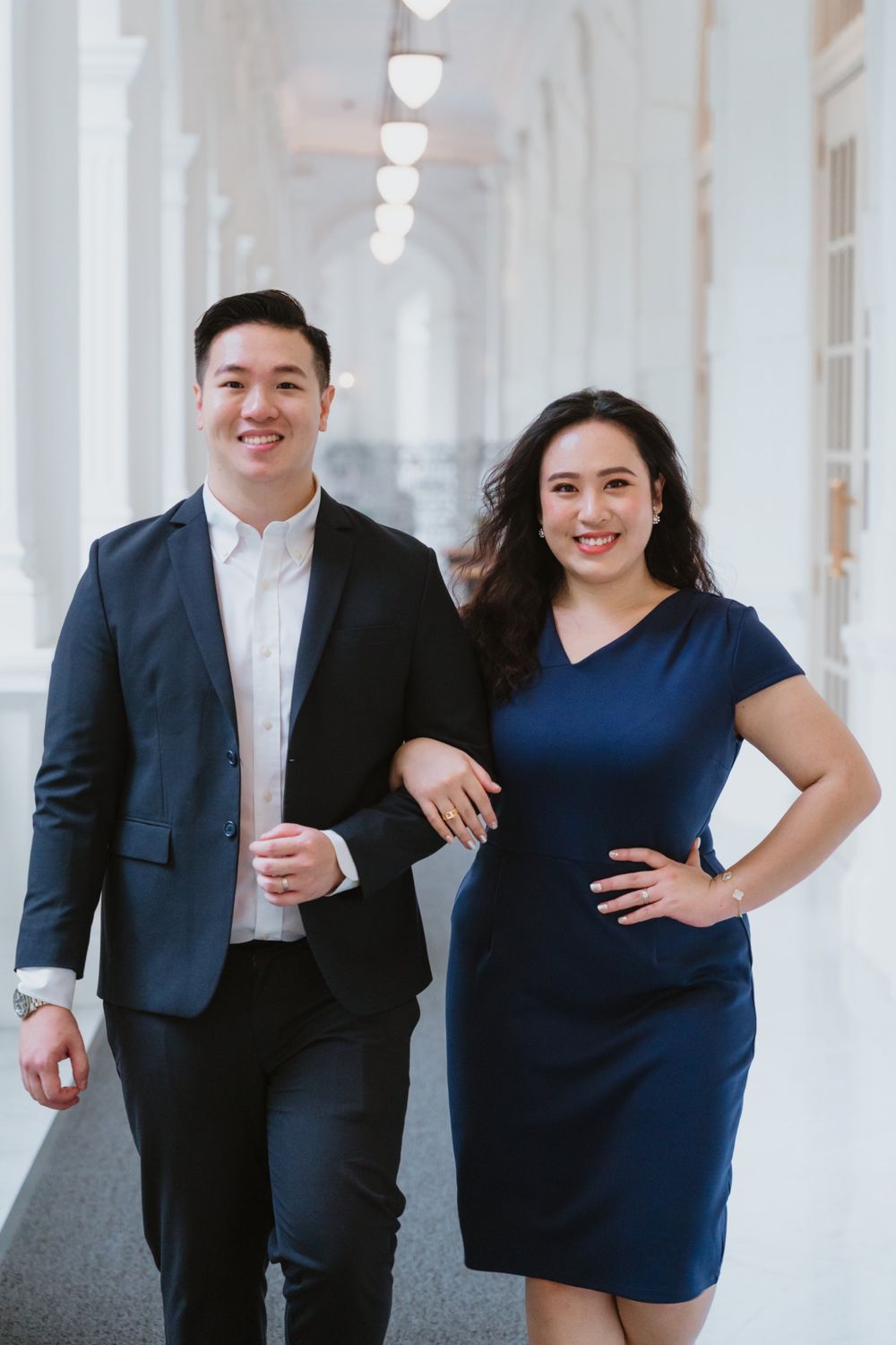 Keith and Rachel walking arm in arm along a white colonnade